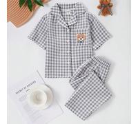 2 pezzi pigiama per bambini piccoli con un elegante design a quadri grigi e bianchi e un grafico carino con motivo orsetto. Questa comoda biancheria da casa estiva include una maglietta a maniche cort