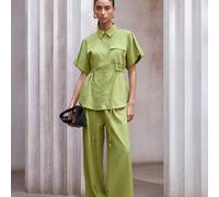 Completo casual da donna composto da camicia con colletto, bottoni e polsini arrotolati in tessuto simile al lino di colore giallo-verde con vita segnata, e pantaloni a gamba dritta con vita segnata,