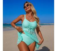 Costume da bagno tankini con controllo pancia in pizzo verde. La parte superiore presenta un scollo a V profondo con laccetti, la parte inferiore ha una gonna in pizzo traforata per nascondere vita e 