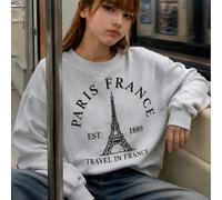 Felpa girocollo grigia da ragazza con design street style dolce, con scritta nera ad arco "PARIS FRANCE" che circonda la grafica della Torre Eiffel e testo "EST 1889 TRAVEL IN FRANCE" sul petto, ampia