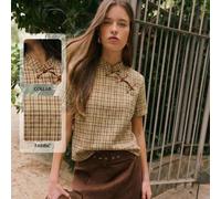 Questa camicetta femminile presenta un colletto alto con elementi ispirati alla Cina. Tre bottoni aggiungono un tocco orientale. La silhouette a maniche corte e linea dritta, insieme al taglio pulito,